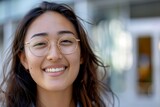Bright and natural portrait of a young Asian woman wearing glasses and smiling