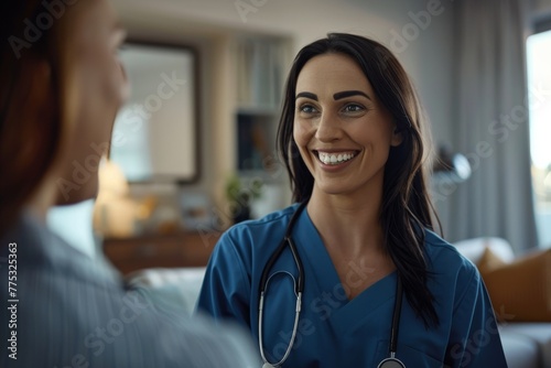 Compassionate nurse in blue scrubs flashes a warm smile at a patient off-camera photo