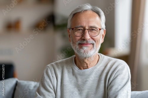 Senior man with glasses and a white sweater smiling in a modern home with houseplants
