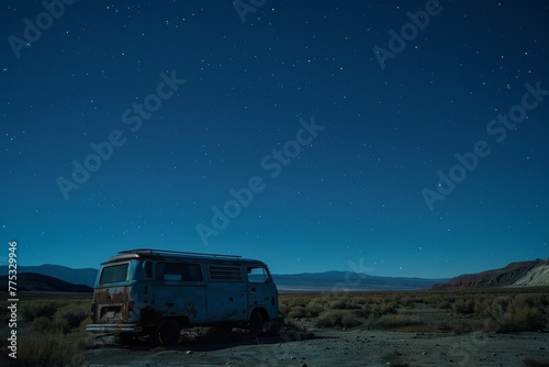 An abandoned vintage van sits solitary under a clear, expansive starry night sky in a remote desert scene