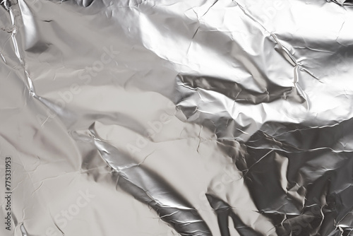 Silver foil texture abstract background. Textured crumpled metallic surface backdrop with light reflection. 