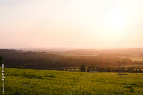 Sonnenuntergang über grüner Landschaft mit Dunst am Horizont