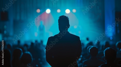 Professional lecture  presenter engaging audience on conference stage. Corporate executive manager speaking to crowd. Blurred de-focused figures in auditorium. Business seminar concept