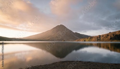 volcanic mountain in morning light reflected in calm waters of lake