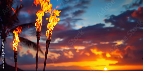 Hawaii luau party Maui fire tiki torches with open flames burning at sunset sky clouds at night photo