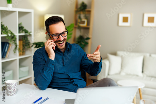 Young happy man talking on the phone in home office