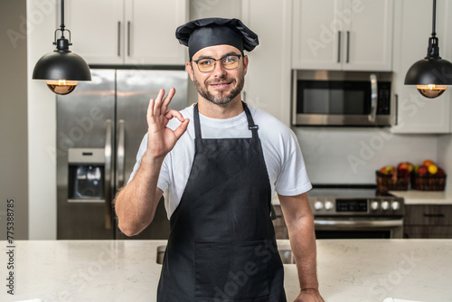 Chef cook with ok sign, delicious food. Portrait of chef man in a chef cap in the kitchen. Man wearing apron and chefs uniform and chefs hat. Character kitchener, chef for advertising.