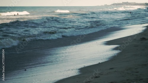 Small sea wave, Blurred Soft foamy waves washing golden sandy beach dawn. Walking people, waterslides beach, corbals, boats grizon. Holiday recreation concept. Abstract nautical summer ocean sunset photo