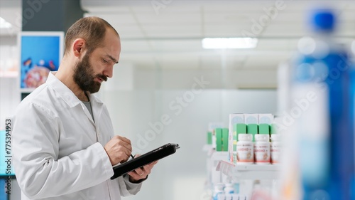 Medical worker counting medicaments boxes placed on shelves, working on drugstore inventory to ensure full stock for clients. Pharmacist doing logistical activity with packages of pills.