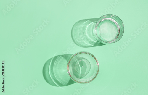 Empty glasses on green pastel background, top view