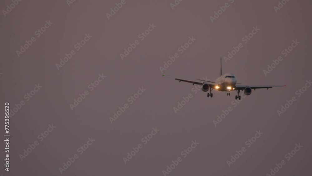 Front view of the aircraft with the landing lights on, during the last approach in the dim light of dusk Front view of the aircraft with the landing lights on, during the last approach in the dim light of dusk