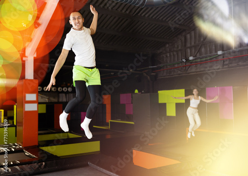 Happy emotional man jumping vertical and flying in trampoline sport center indoors © JackF