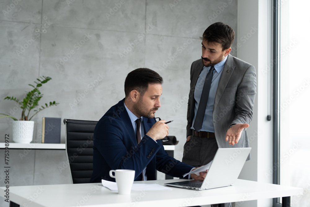 Two businessmen at office desk with laptop Two businessmen at office desk with laptop