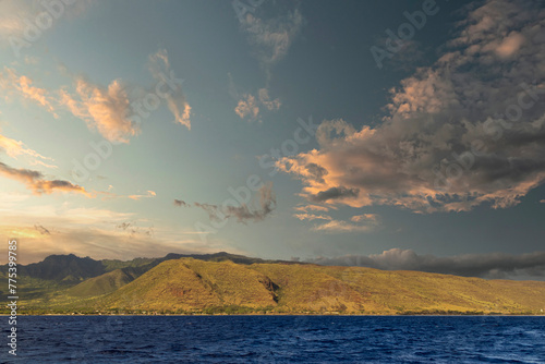 a beautiful spring landscape of the coast of Oahu with majestic mountain ranges, lush green trees and plants, rippling blue ocean water and blue sky with clouds at sunset in Kapolei Hawaii USA photo