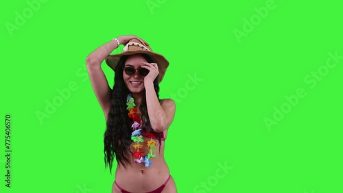 Young Latin woman in bikini putting on sunglasses and beach hat on a Green Screen, Chroma Key photo