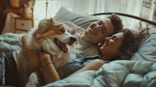 Young couple in love lying on the sofa in the bedroom with their beloved dog, having fun and enjoying each other on their weekend. 