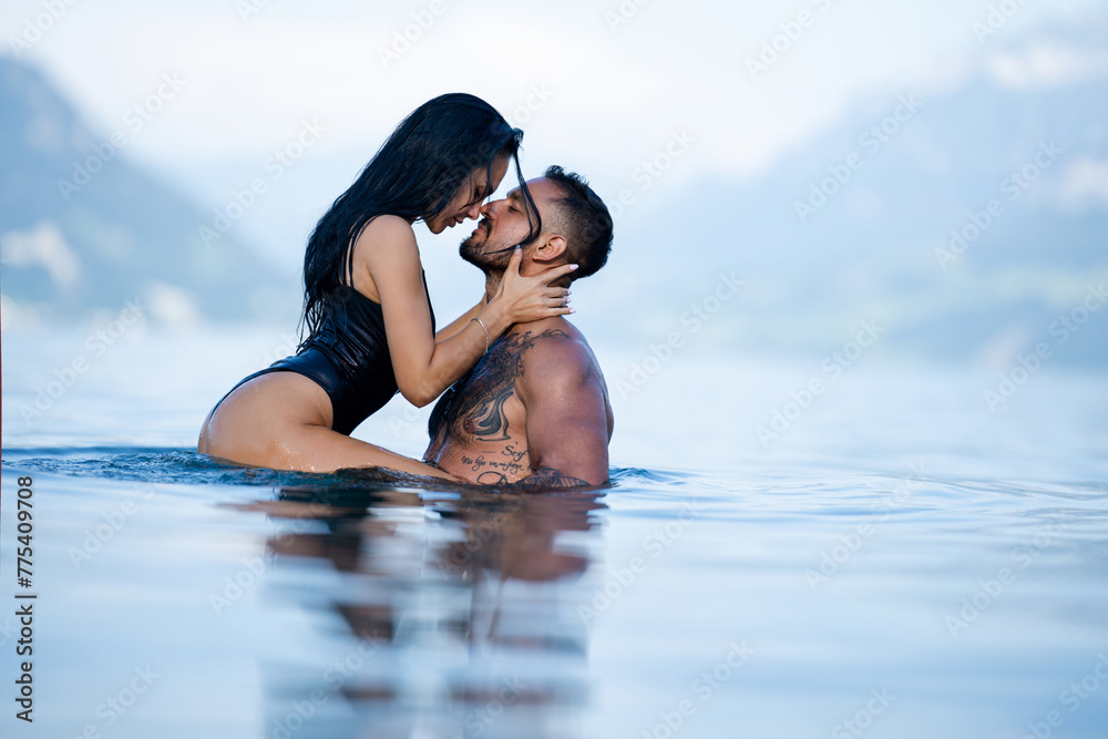 Summer sexy couples. Romantic couple in sea water. Beautiful young couple in love on the lake. Sexy couple kissing by the sea. Dream vacation. Embrace and kiss in the water. Romantic beach paradise. - obrazy, fototapety, plakaty 
