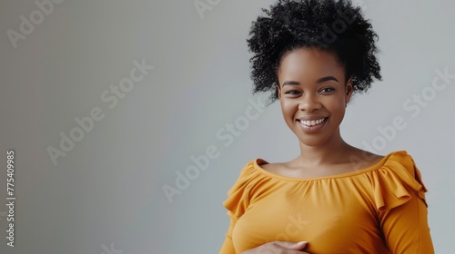 cheerful pregnant african american girl touching belly on grey  photo