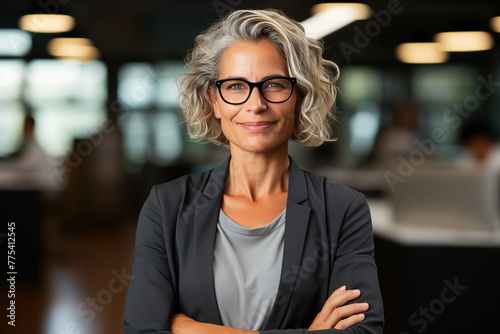 Thoughtful business strategist woman in her 50s in a modern office, contemplating her next move with determination.