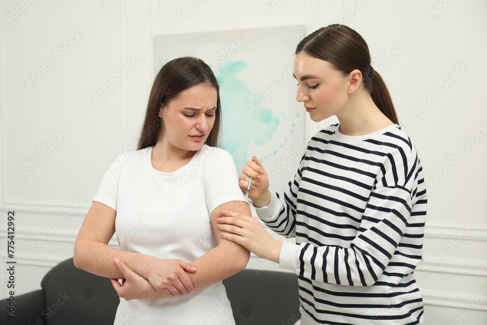 Woman giving insulin injection to her diabetic friend at home Woman giving insulin injection to her diabetic friend at home