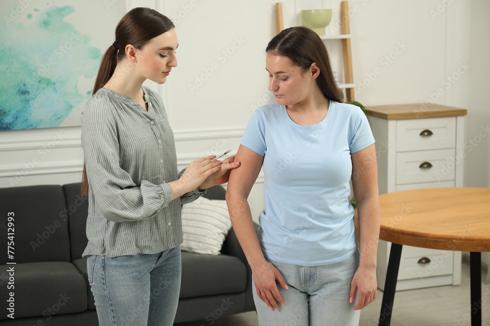 Woman giving insulin injection to her diabetic friend at home Woman giving insulin injection to her diabetic friend at home