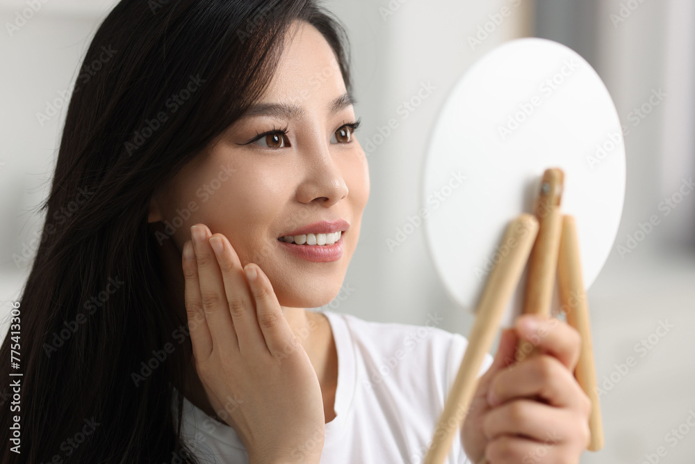 Woman with perfect skin looking at mirror indoors Woman with perfect skin looking at mirror indoors