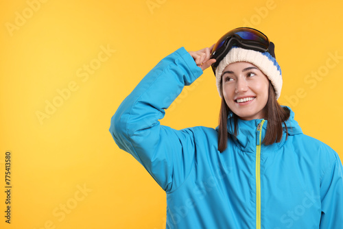 Winter sports. Happy woman with snowboard goggles on orange background, space for text © New Africa