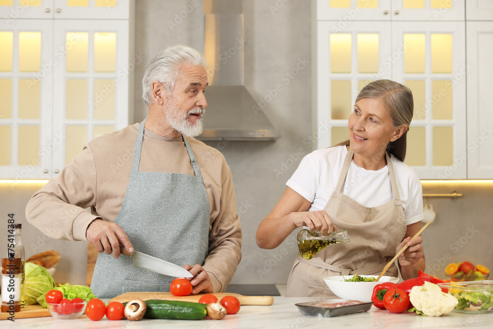 Happy senior couple cooking together in kitchen Happy senior couple cooking together in kitchen