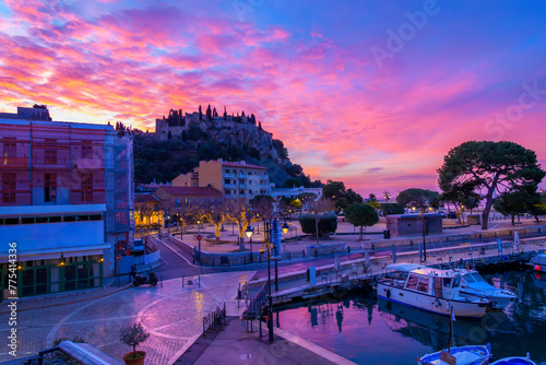 Obraz na plátně A colorful sky at dawn above the Château de Cassis hilltop fortified castle and the shops and marina early morning, at Cassis, France, along the Cote d'Azur Riviera