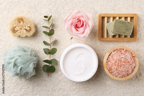 Flat lay composition with moisturizing cream in open jar and other body care products on light textured table