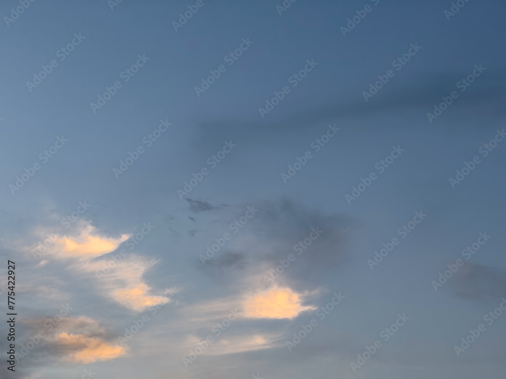 A small group of cloudlets low in blue sky catch the last direct rays of sunset among others fading on a March evening in southwest Florida, for motifs of natural transition A small group of cloudlets low in blue sky catch the last direct rays of sunset among others fading on a March evening in southwest Florida, for motifs of natural transition