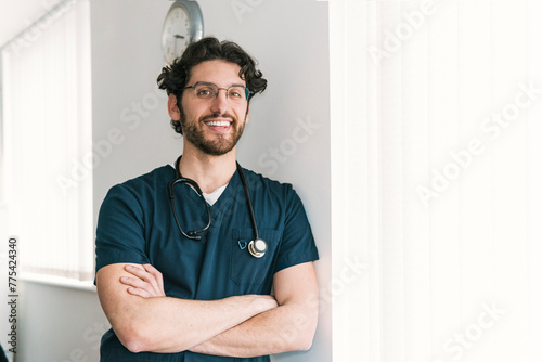 A pensive male healthcare worker with arms crossed stands by a clock, symbolizing timely medical services photo
