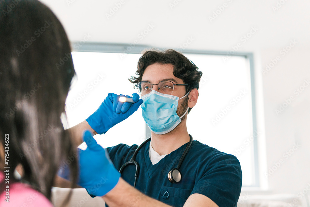 A focused doctor examines the throat of a patient using a medical light, an essential part of a routine ENT checkup