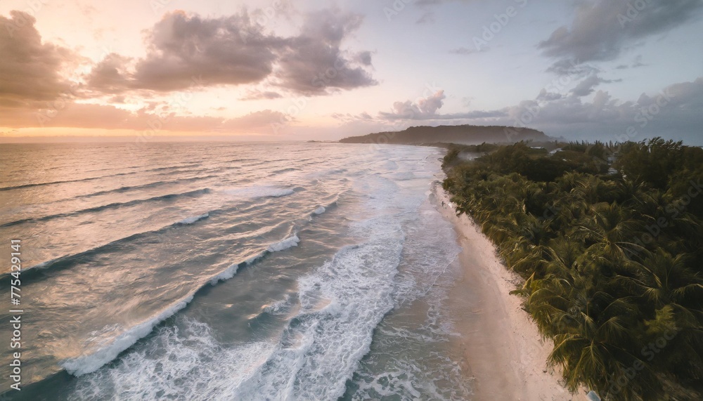 overhead aerial photograph of waves crashing on the shoreline at sunset island tropical beach