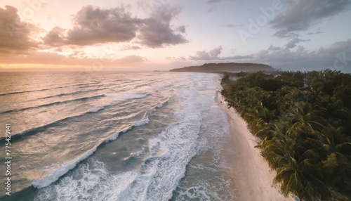 overhead aerial photograph of waves crashing on the shoreline at sunset island tropical beach