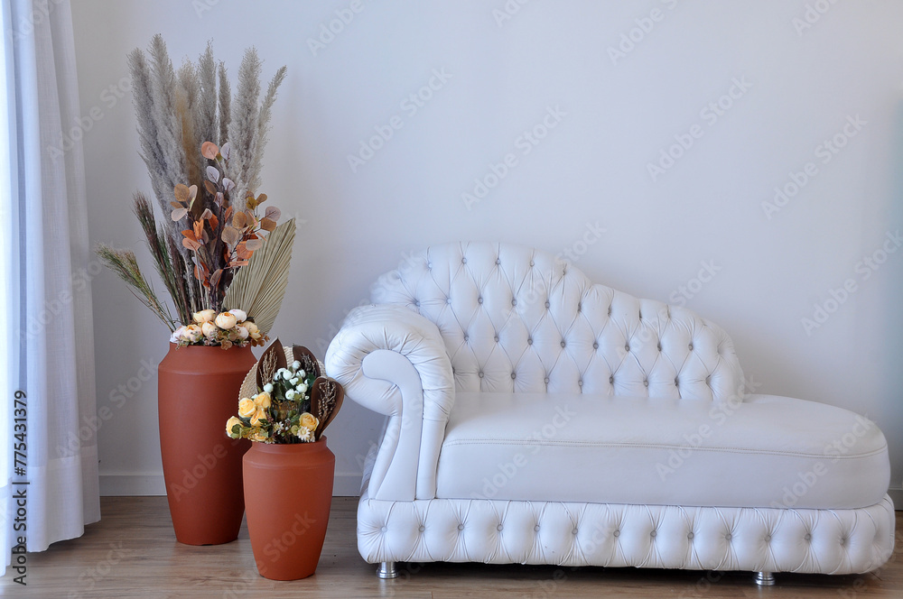 sala com sofa de capitone e vasos decorados com capim dos pampas  - obrazy, fototapety, plakaty 