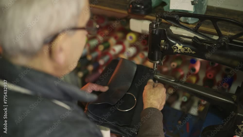 Top view of a senior cobbler repairing a purse in his shop.
Top view of a senior cobbler repairing a purse in his shop.