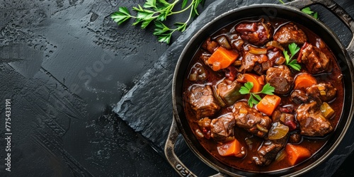 A bowl of stew with meat and vegetables. The stew is in a black bowl and is on a black surface
