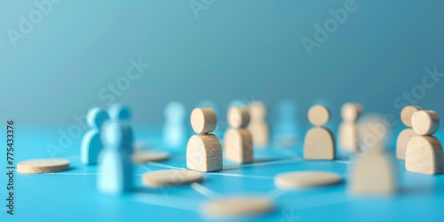A group of wooden people are arranged in a circle on a blue background. The people are of different sizes and are positioned in various places around the circle. The arrangement of the people