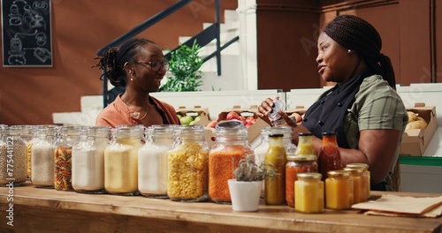 African american seller giving food sample to customer, presenting new homemade snacks with natural ingredients. Vegan woman trying out market products before buying. Handheld shot.