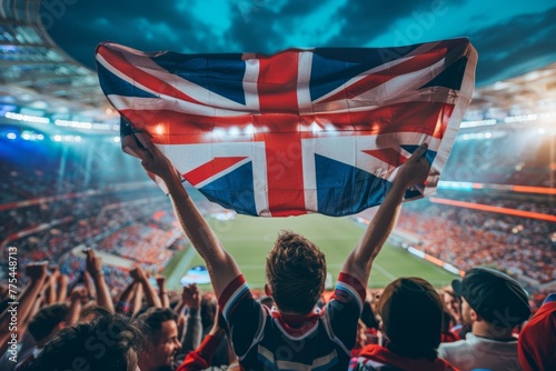 A man holding British flag in a stadium full of people. Football fans or spectators at the football championship