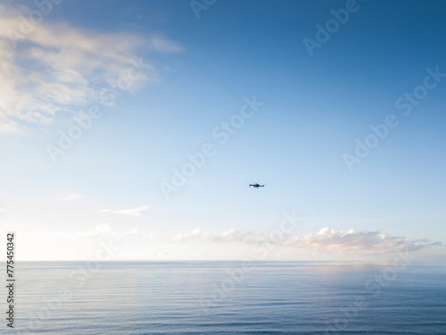 Seascape with a drone flying in the blue sky and clouds.