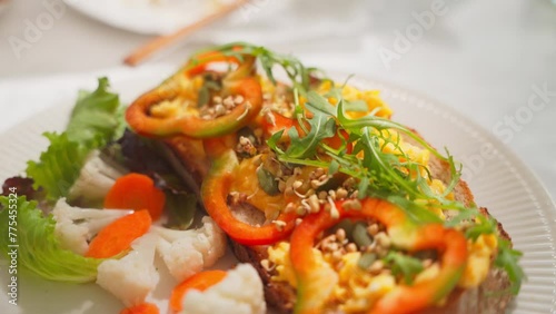 Closeup of a delicious healthy breakfast toast with scrambled egg, bell pepper, argula, and pickled cauliflower and carrot photo