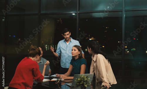 Professional diverse businesspeople discussing about start up project. Manager explaining, sharing brainstorming business strategy at night office. Group of business team working together. Tracery.