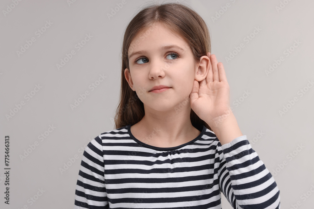 Little girl with hearing problem on grey background Little girl with hearing problem on grey background