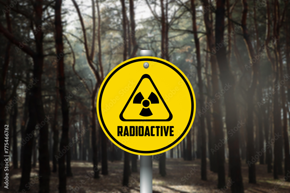 Radioactive pollution. Yellow warning sign with hazard symbol in forest Radioactive pollution. Yellow warning sign with hazard symbol in forest