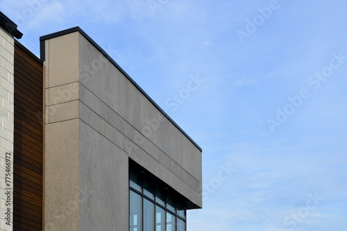 The exterior wall of a contemporary commercial-style building with aluminum metal composite panels and glass windows. The futuristic building has engineered diagonal cladding steel frame panels.