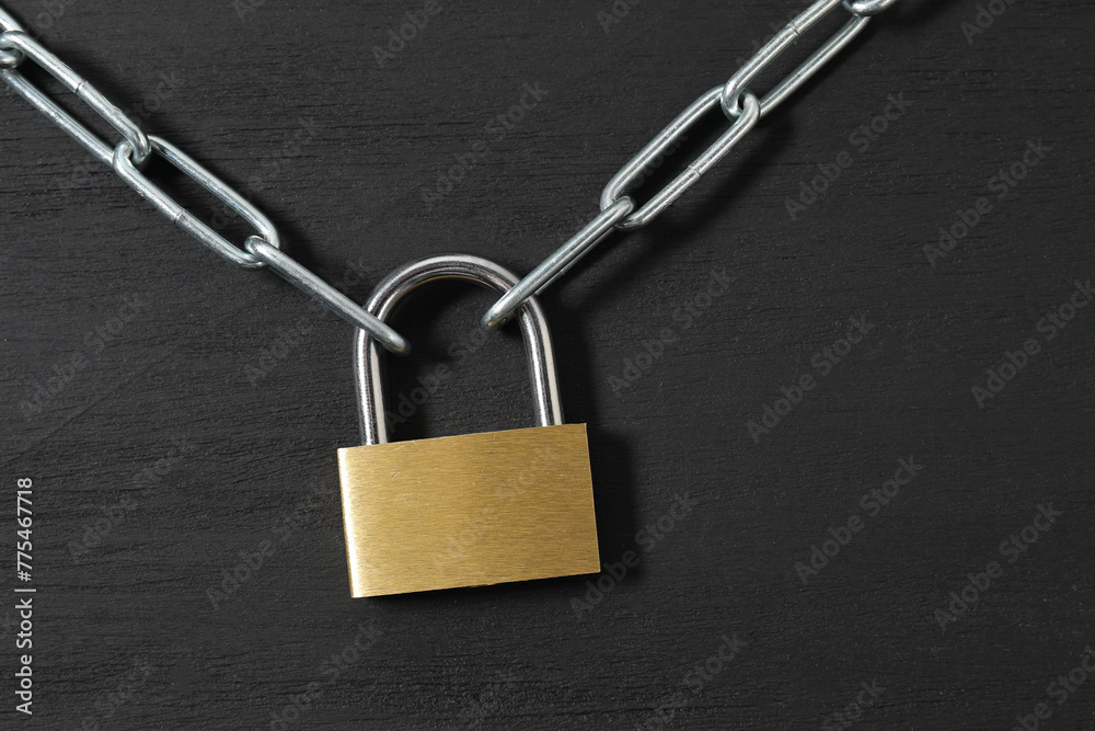 Steel padlock with chain on black wooden table, top view Steel padlock with chain on black wooden table, top view