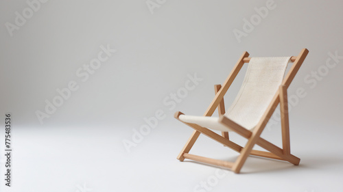Miniature wooden deck chair on a plain background, suggesting simplicity and relaxation. photo