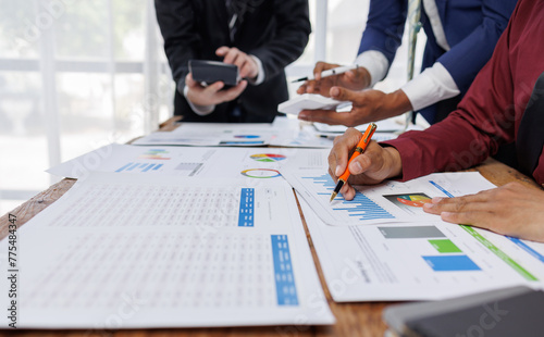 Group of confident business people point to graphs and charts to analyze market data, balance sheet, account, net profit to plan new sales strategies to increase production capacity. 